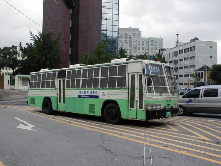 a green and white bus driving on the street