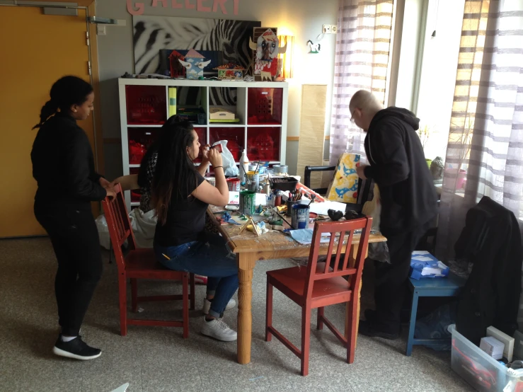 a group of people sit around a table that is surrounded by containers and boxes