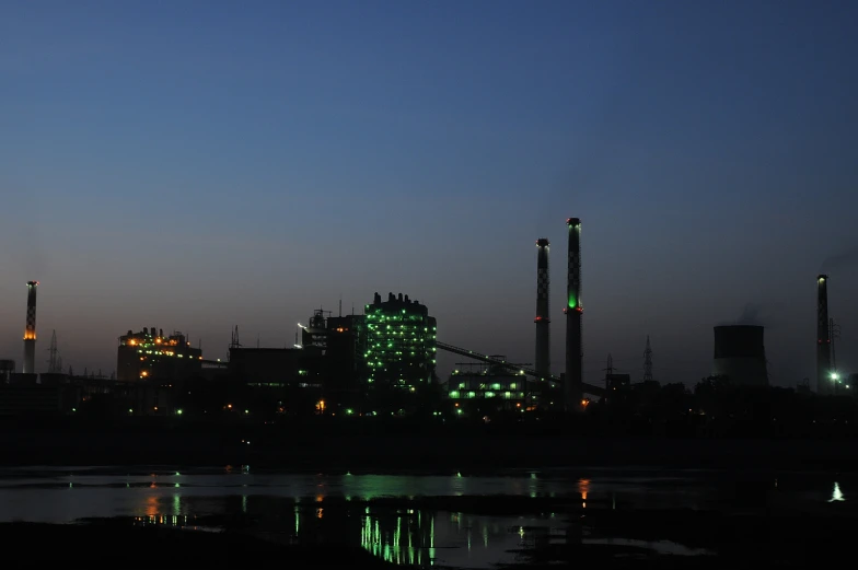 the factory towers have been lit up green in the evening