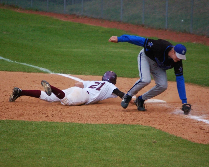 a baseball player that has fallen to the ground and is tagged out