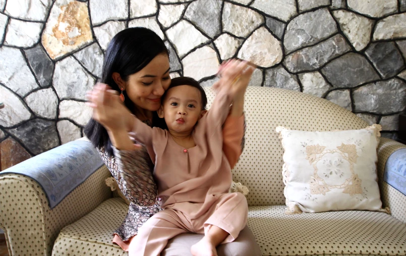 two women holding a child up while sitting on a couch