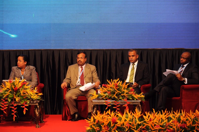 a panel of men sitting in chairs while talking to one another