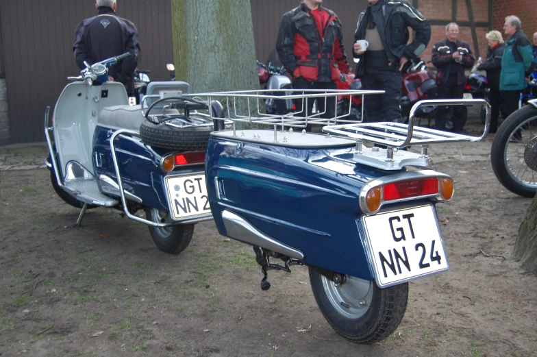 a vintage blue motorcycle parked on top of a dirt field