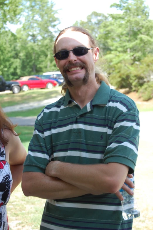 man in sunglasses standing in grass near a tree