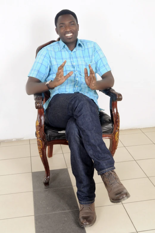 a man sitting in a chair smiling and holding up his hands