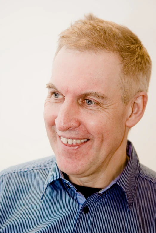 a man with blond hair smiles as he poses for a picture