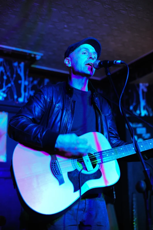 a man that is playing a guitar near a microphone