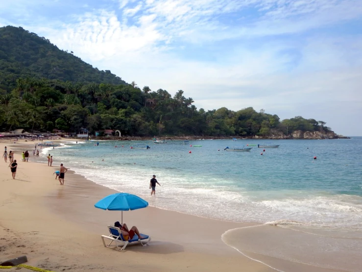 people are gathered around in the sun on the beach