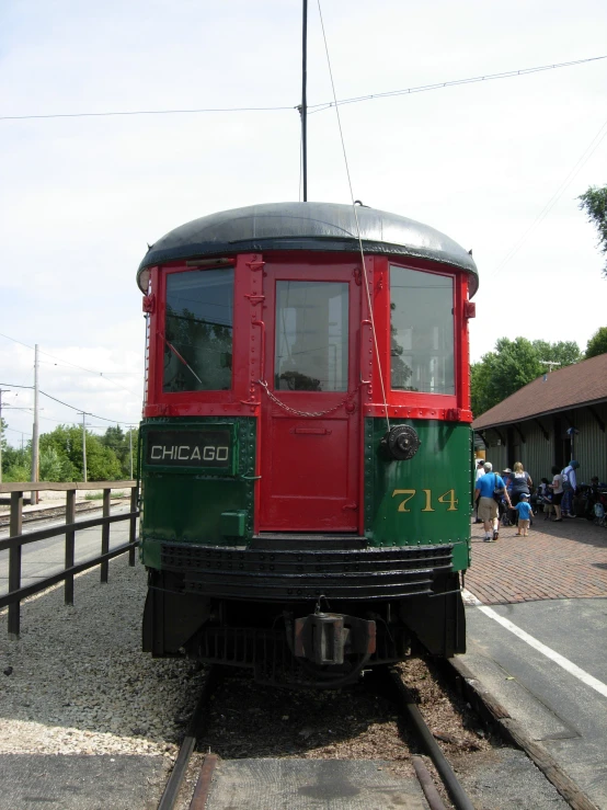 a close up of a train on the tracks with people walking by