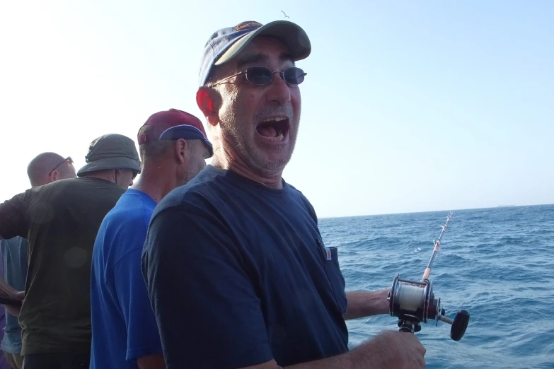 a man in sunglasses and hat holds a fishing rod