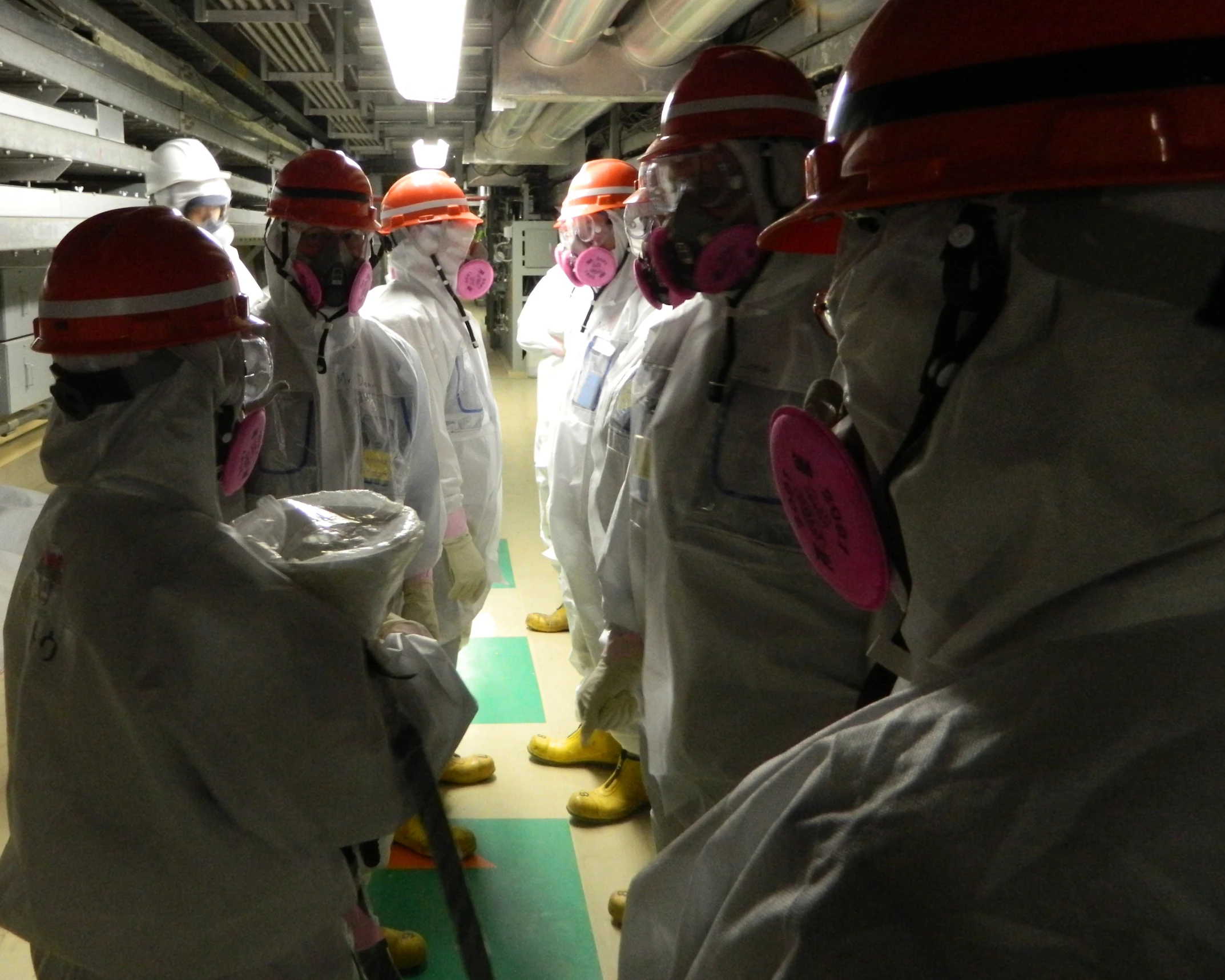 a group of people in safety suits stand in an industrial setting