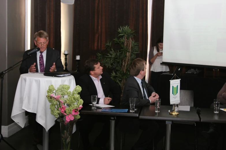 two men and a woman in business attire are speaking to each other