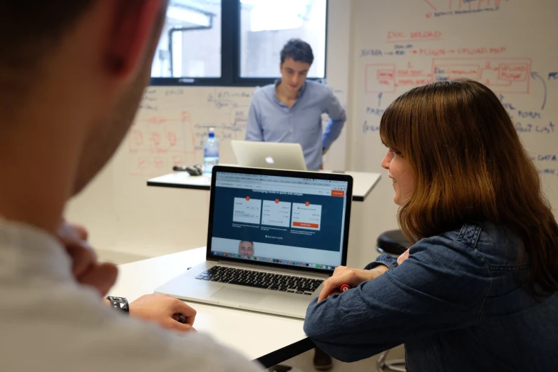 two people sit at a table working on their laptops