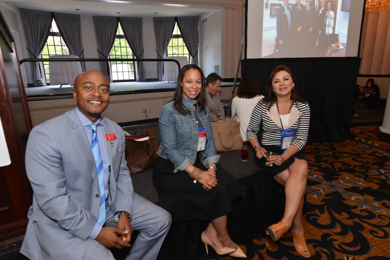 three people sitting on two different couches at a conference