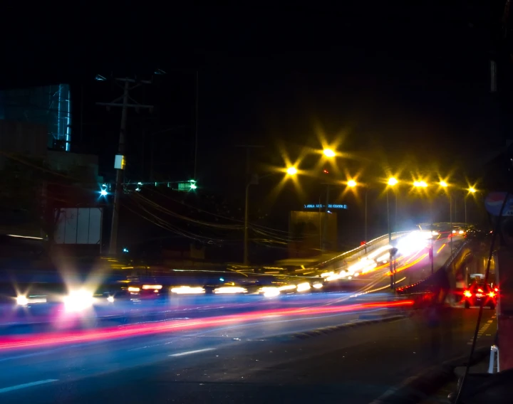 car lights streak down a freeway with buildings behind it