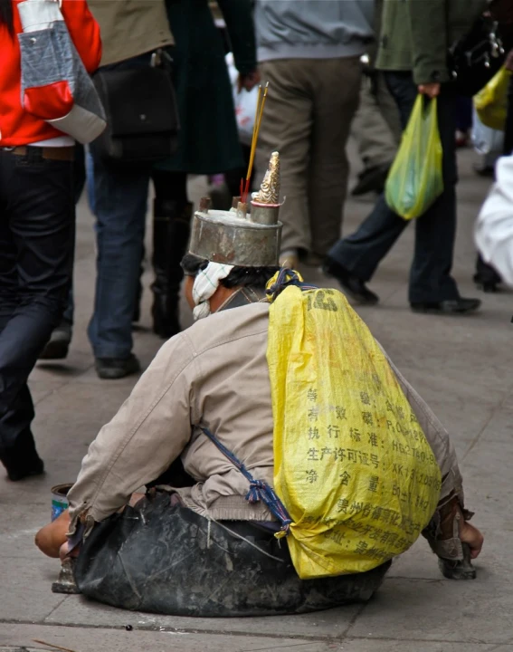 a man sitting on the sidewalk near a crowd