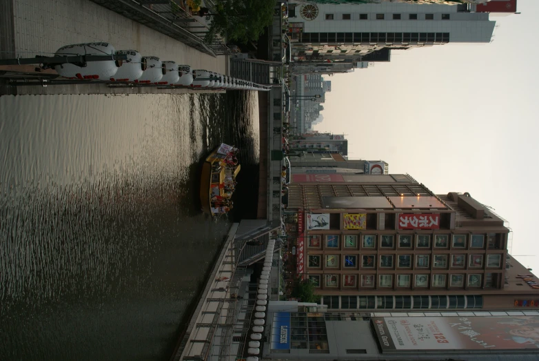 boats moored at the edge of a large canal near tall buildings