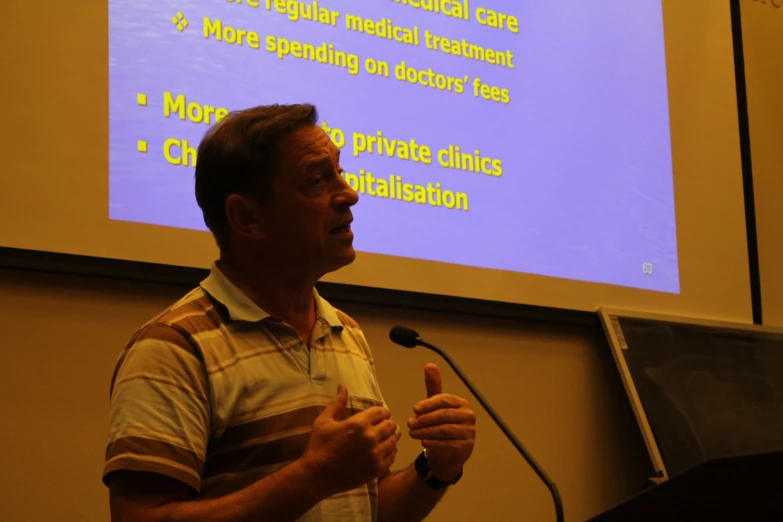 a man standing in front of a projection screen giving a presentation