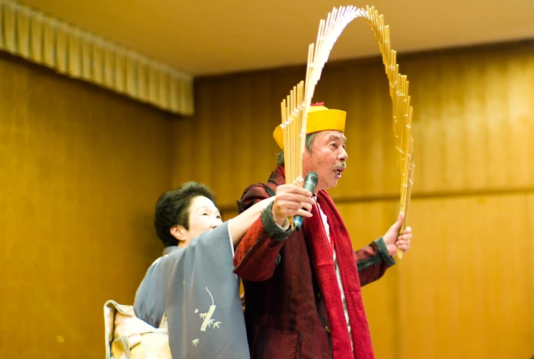 two men one with a hat and another is holding scissors