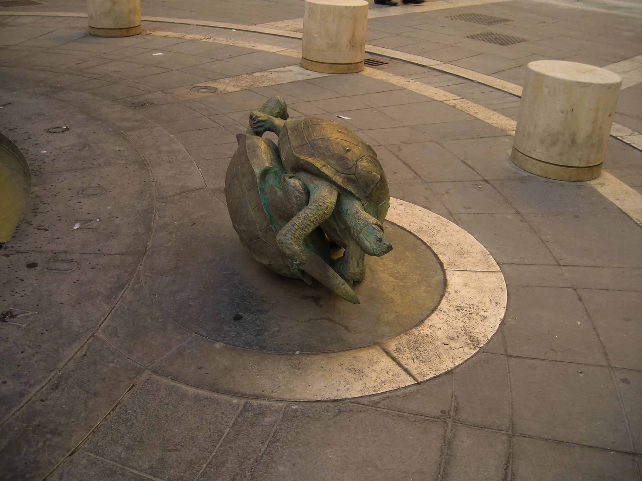 a statue on the ground with three heads sitting on it