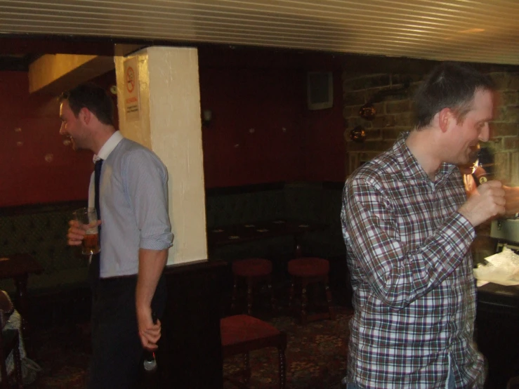 a man in plaid shirt and tie standing near other men