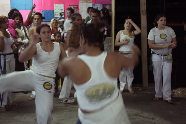 two women in white shirts are dancing with other people