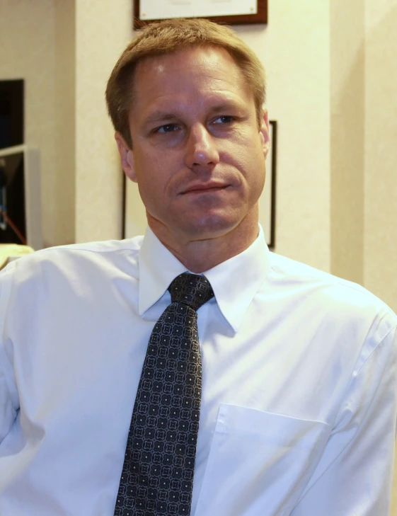 a man in a white shirt and tie is posing for the camera