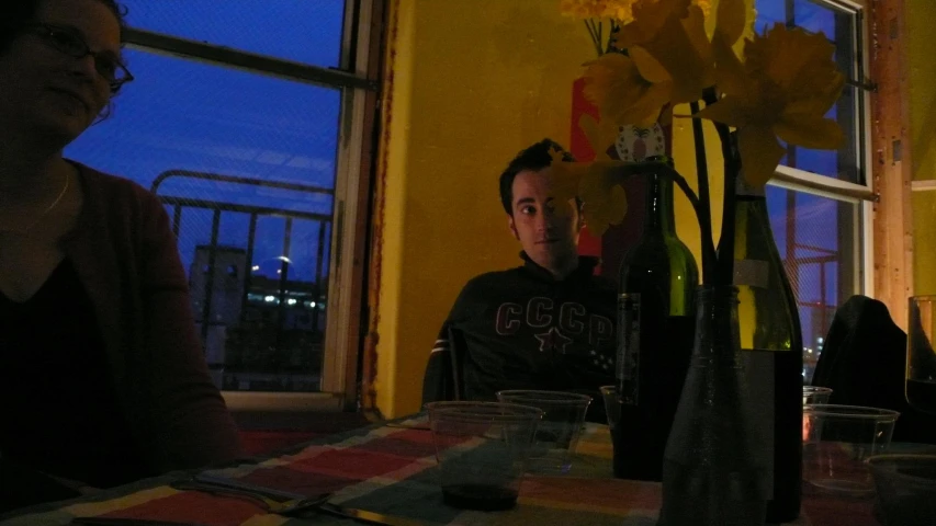 a couple sitting at a table in front of vases filled with flowers