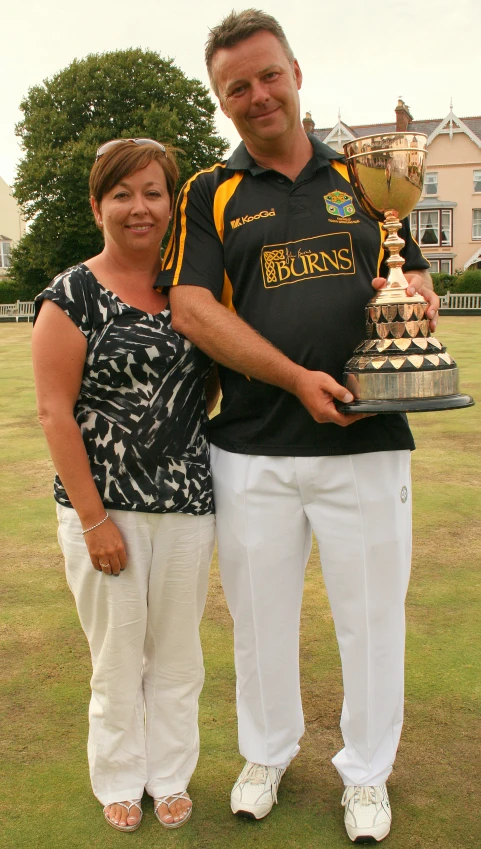 a man and a woman posing with a trophy