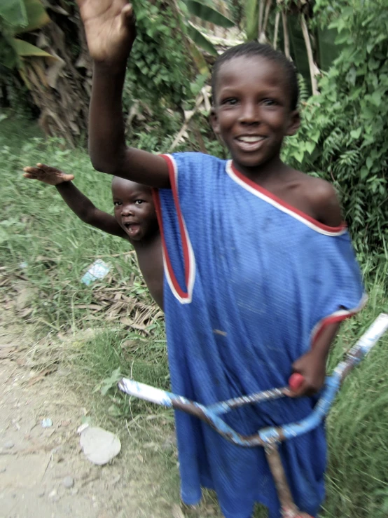 a small black boy in a blue dress is holding a tennis racket