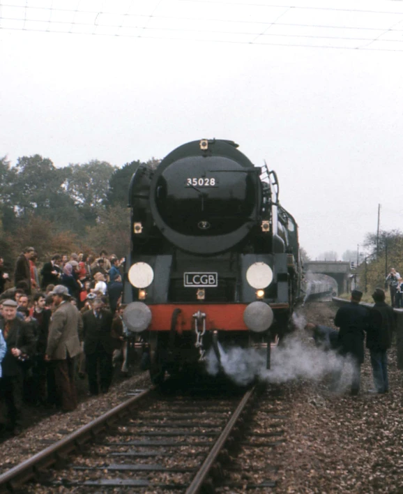 train passing by a large crowd of people on tracks