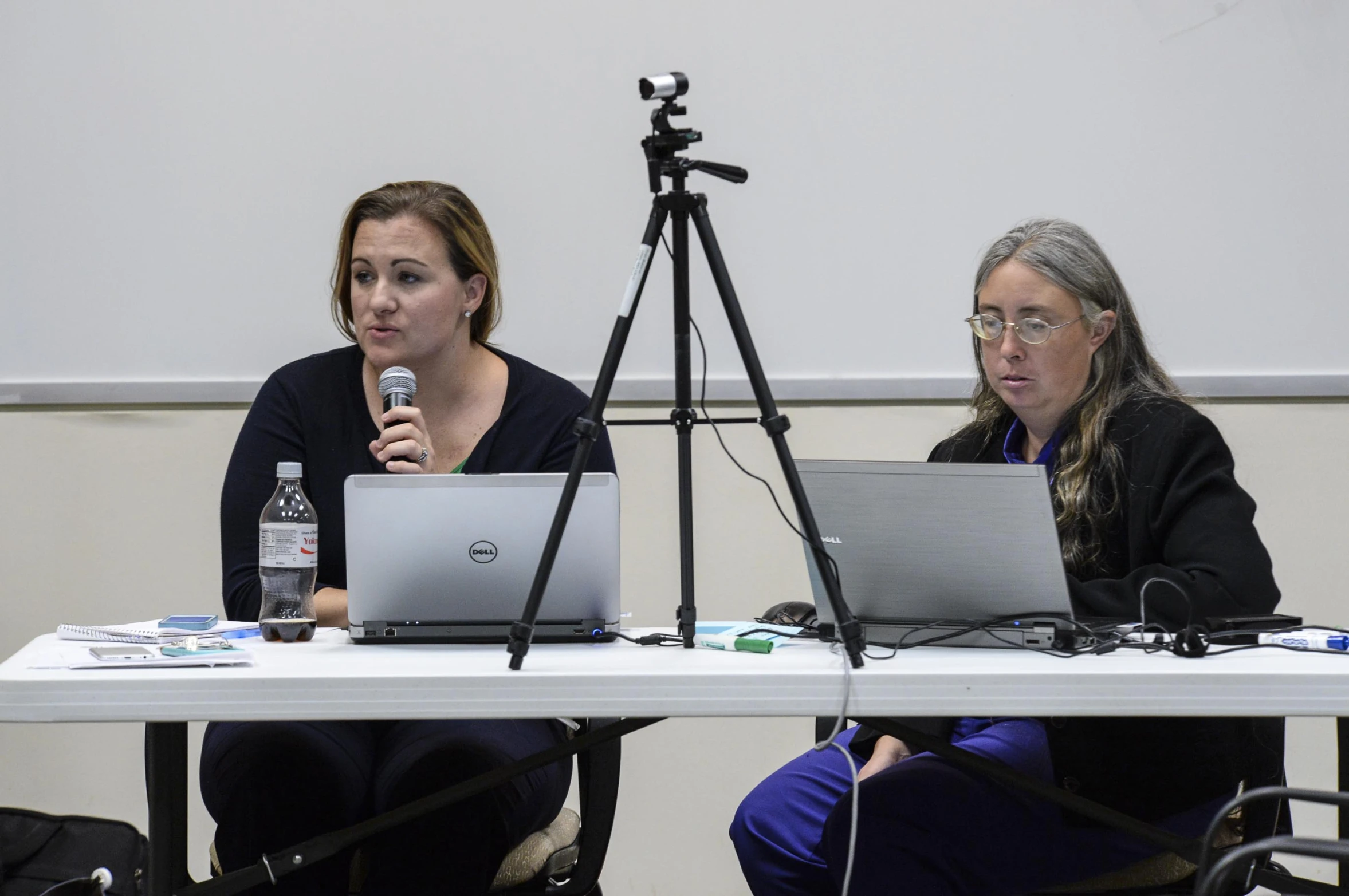 two women sitting at a white table talking