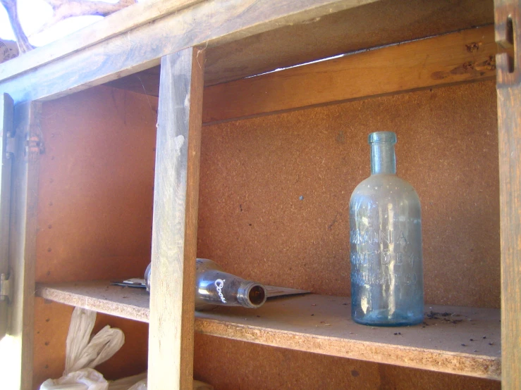 an empty bottle and some kind of lighter on wooden shelves