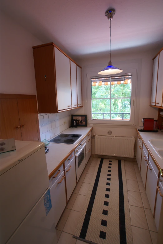 the small kitchen has white cabinets and black stripe rug