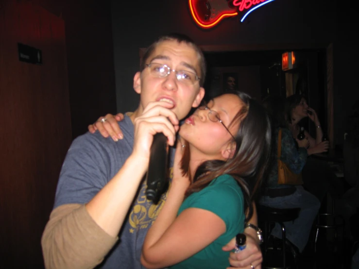 a man kissing a woman's cheek while holding a wine bottle