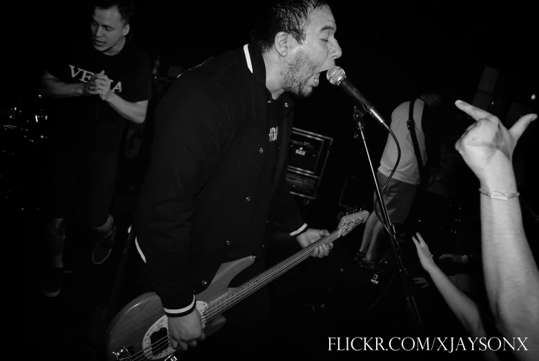 a person is standing and singing with his guitar