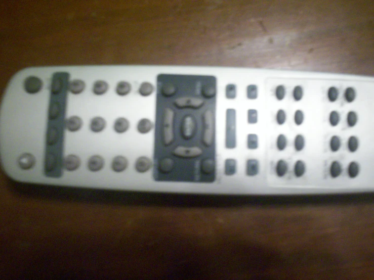 the back side of a remote control sitting on a wooden table
