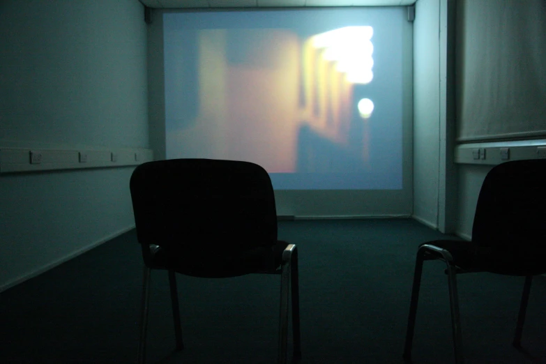 two black chairs in front of a projection on the wall