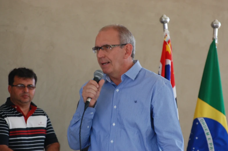 a man is speaking into a microphone with two flags