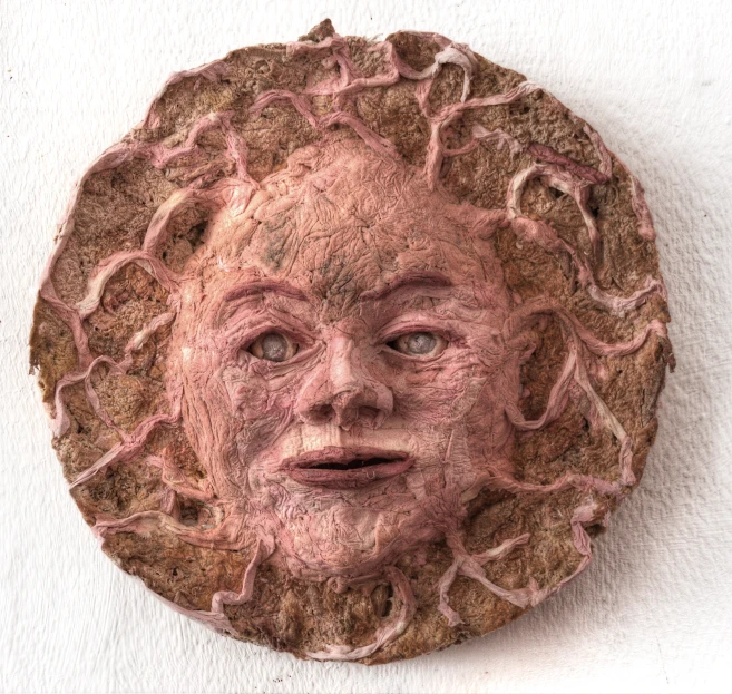 a clay face is hanging on the wall