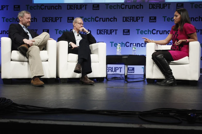 four people sitting in white couches on a stage