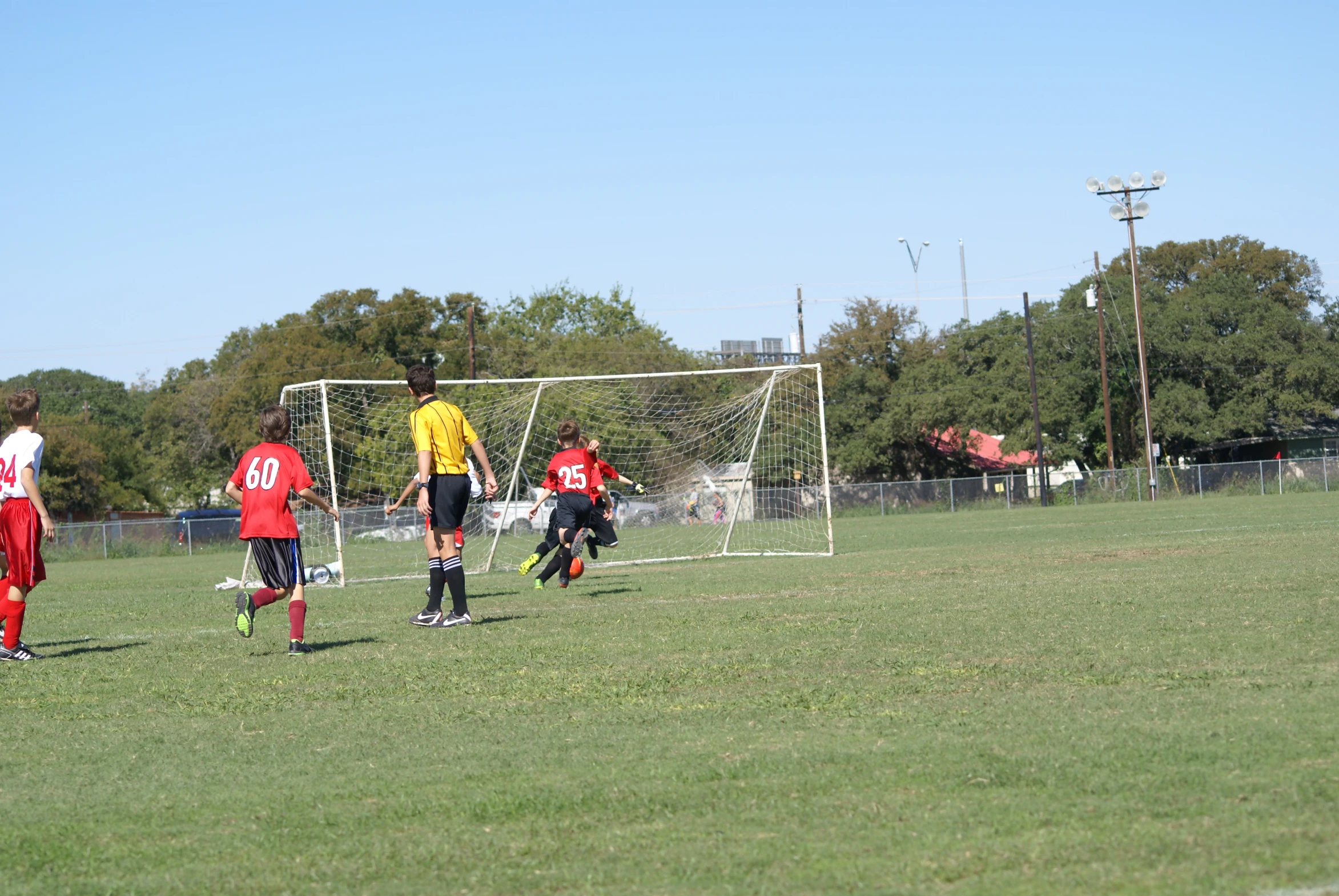 children playing soccer on the soccer field wearing red uniforms