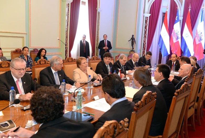 several people sit in suits at tables during a meeting