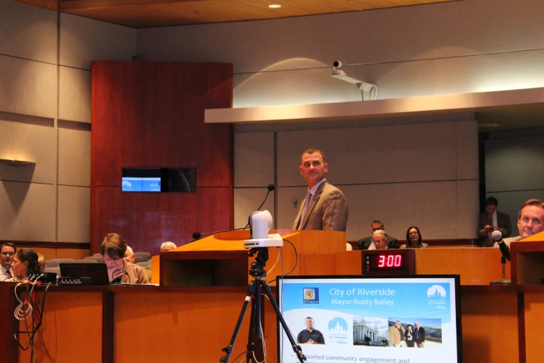 a speaker at a podium standing in front of a group of people