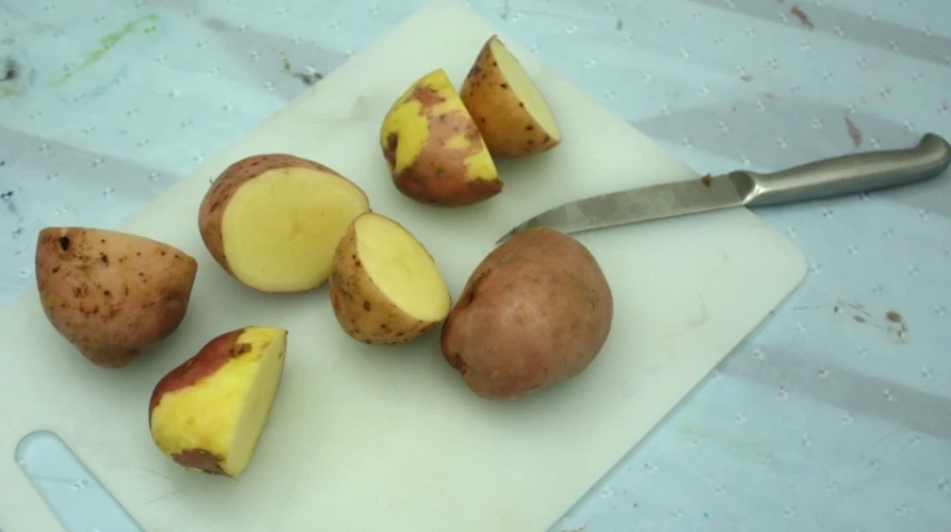 four potatoes with cut up slices of each other on a  board