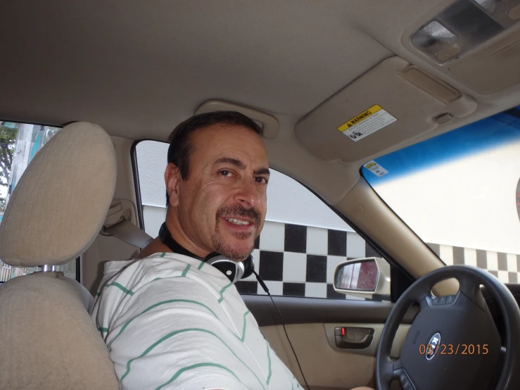 a man in striped shirt sitting inside of a car