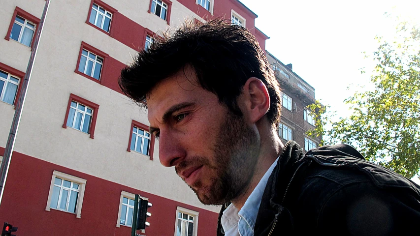 a man looking at the camera in front of buildings