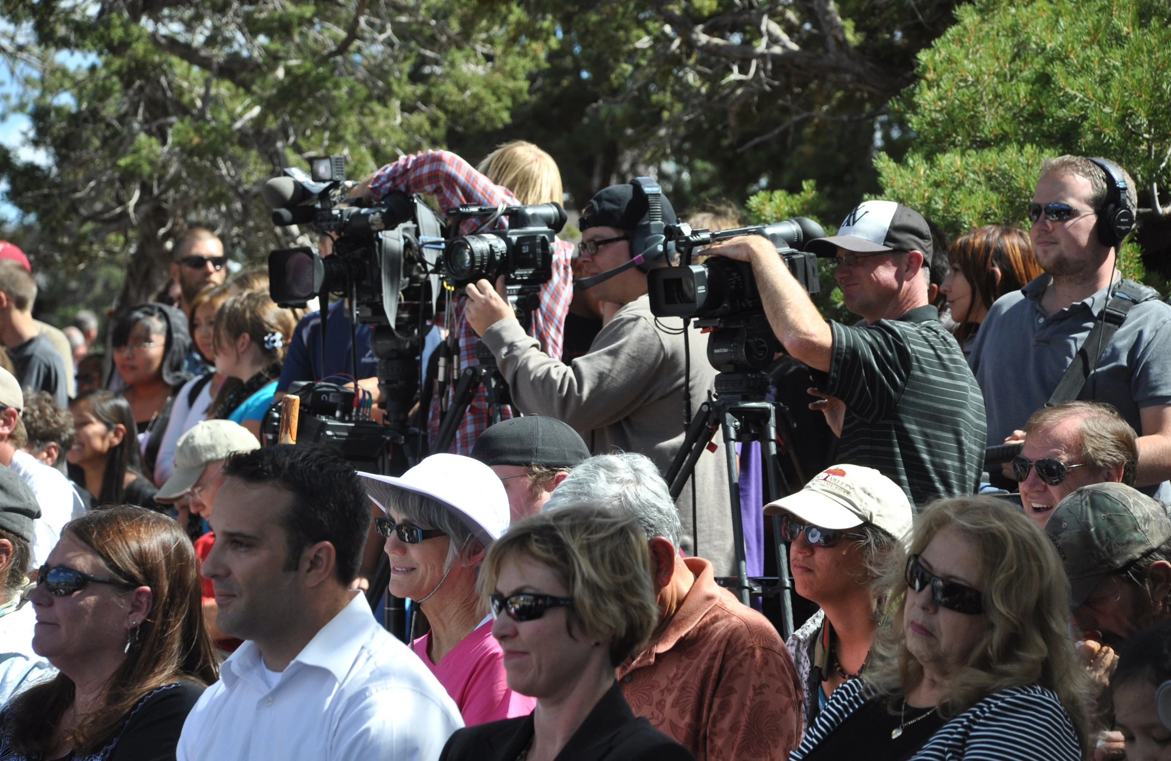 an audience of people wearing white hats are gathered around cameras