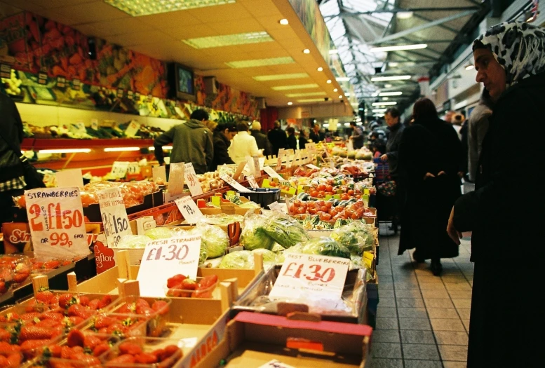 people walk around a large store with many produce items