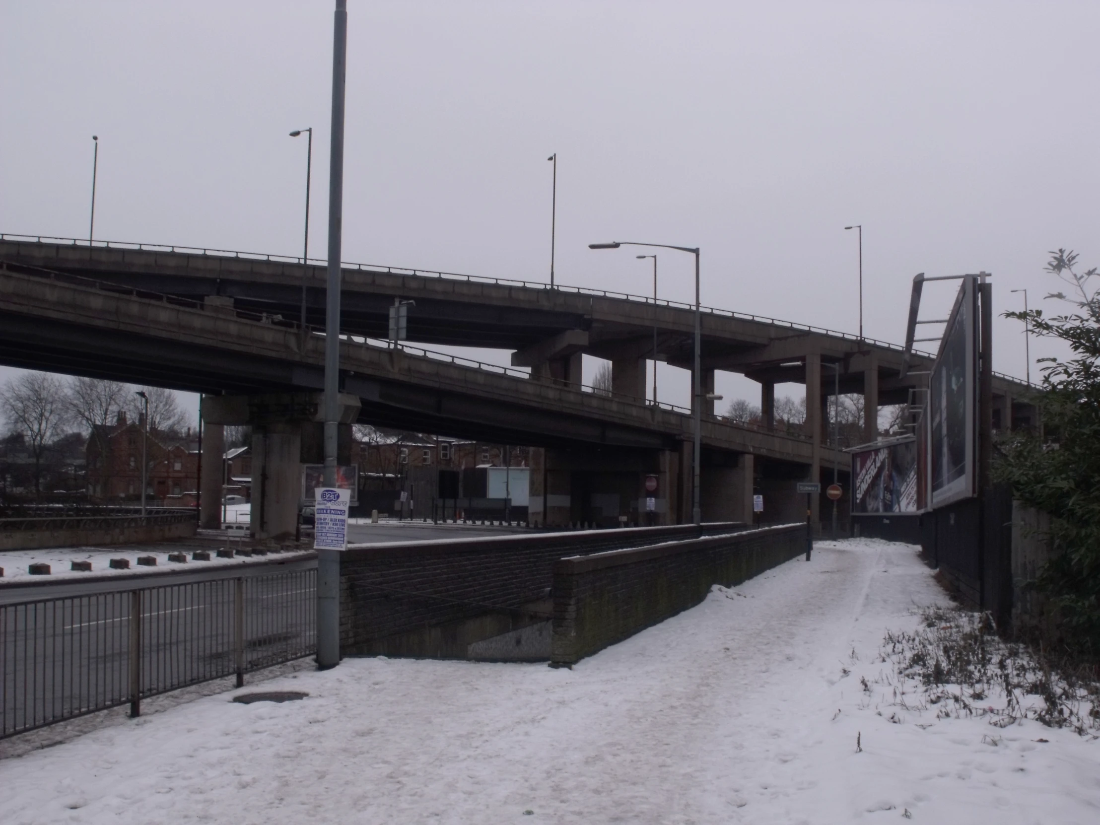 an icy road near a bridge on top of snowy ground